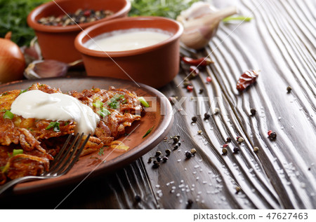 Homemade tasty potato pancakes in clay dish 47627463