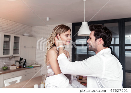 Smiling young long-haired pretty woman in a white shirt looking at her husband Smiling young long-haired pretty woman in a white shirt looking at her husband 47627901