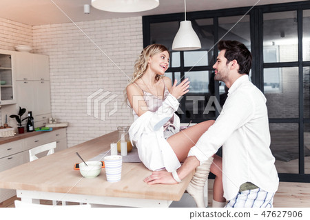 Smiling young pretty woman in a white shirt sitting on the table 47627906