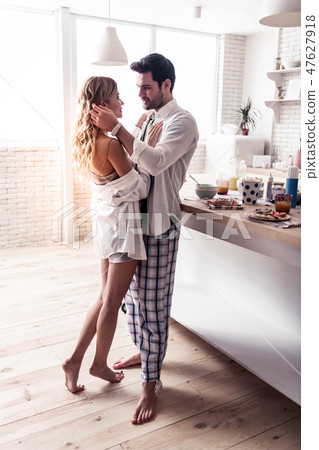 Dark-haired bearded man in a white shirt looking tenderly at his wife 47627918