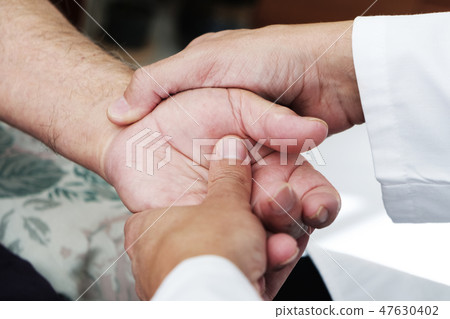man moving the hand of a senior patient 47630402