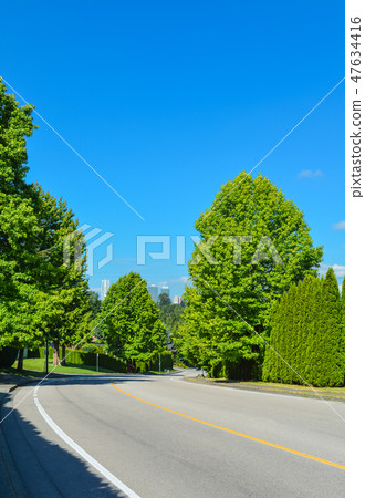 Suburban road curve leading to a city. Suburban road curve leading to a city. 47634416