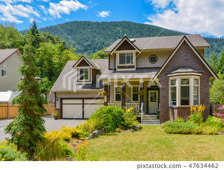 Big family house with concrete driveway, two garage doors, decorated front yard 47634462