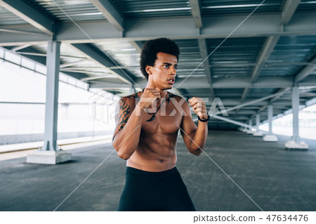 Bare chested kickboxer standing with raised fists  47634476