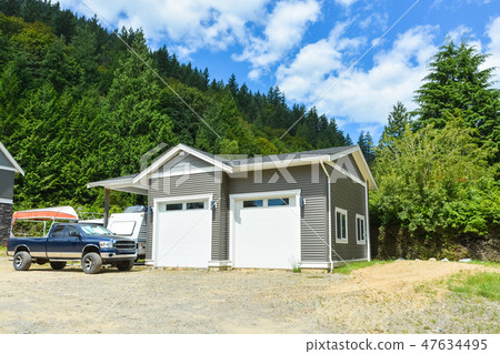 Brand detached double garage with car and boat parked on gravel driveway Brand detached double garage with car and boat parked on gravel driveway 47634495