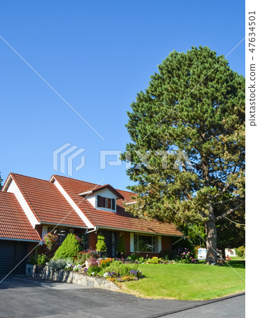 Big residential house with tiled roof and delicately landscaped front yard. 47634501