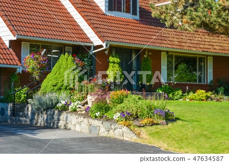 Entrance of family house with tiled roof and delicately landscaped front yard Entrance of family house with tiled roof and delicately landscaped front yard 47634587