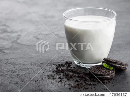 Glass of milk and black sandwich cookies on black  47636187