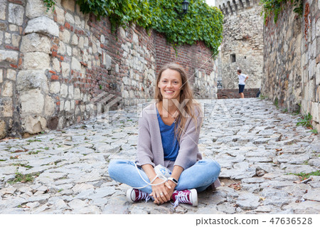 Pretty tourist girl sitting on empty street of historic city in hot summer day. Young woman posing Pretty tourist girl sitting on empty street of historic city in hot summer day. Young woman posing 47636528
