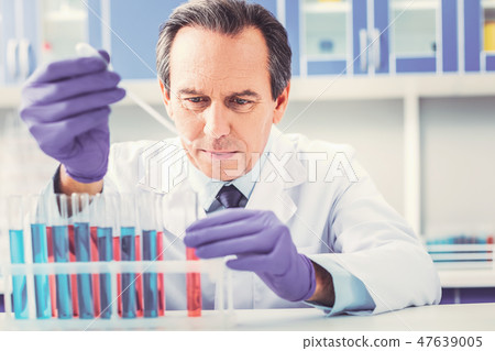 Ageing chemist placing test tubes in order Ageing chemist placing test tubes in order 47639005