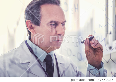 Ageing microbiologist holding marker pen writing formula Ageing microbiologist holding marker pen writing formula 47639087