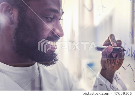 Young technologist smiling while writing chemical formula 47639106