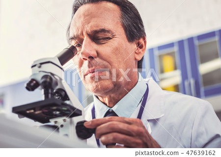 Busy hard-working microbiologist looking into microscope 47639162