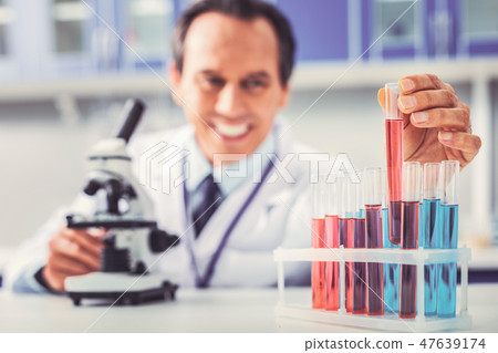Glass tubes with different chemical substances standing near microscope 47639174