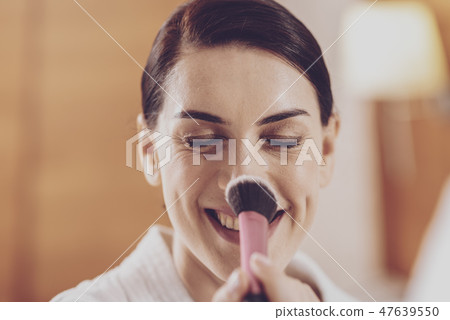 Cheerful model applying powder on her nose 47639550