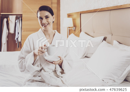 Presentable woman sitting on bed in hotel Presentable woman sitting on bed in hotel 47639625