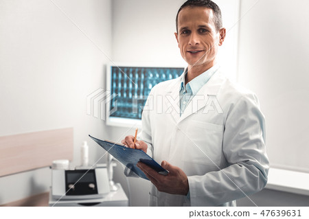 Dark-haired doctor making some important notes Dark-haired doctor making some important notes 47639631