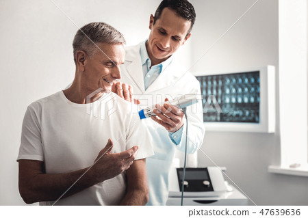 Smiling elderly man talking to doctor during checkup Smiling elderly man talking to doctor during checkup 47639636