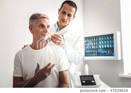 X-ray specialist examining shoulder of patient X-ray specialist examining shoulder of patient 47639638