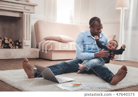 Joyful positive man sitting on the floor Joyful positive man sitting on the floor 47640373