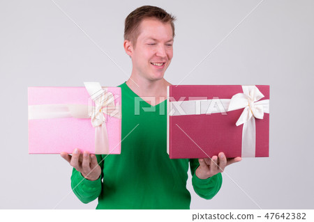 Happy young man comparing two gift boxes ready for Valentine's day 47642382
