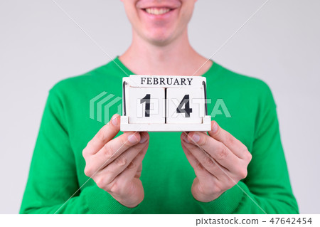 Hands of happy young man holding calendar block ready for Valentine's day Hands of happy young man holding calendar block ready for Valentine's day 47642454