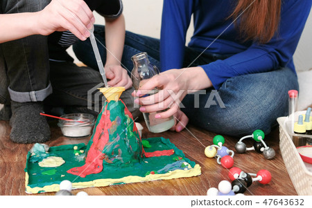 Chemical experiment. Close-up of the boy's hands poured water from the bottle into the funnel of the 47643632