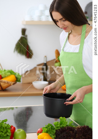 Beautiful Hispanic woman cooking soup in kitchen. Healthy meal and householding concepts Beautiful Hispanic woman cooking soup in kitchen. Healthy meal and householding concepts 47645283
