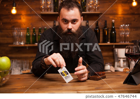 Bearded hipster bartender playing with his trick cards. Bearded hipster bartender playing with his trick cards. 47646744