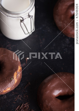 Chocolate donuts near bottle of milk and chocolate crumbs. 47646904