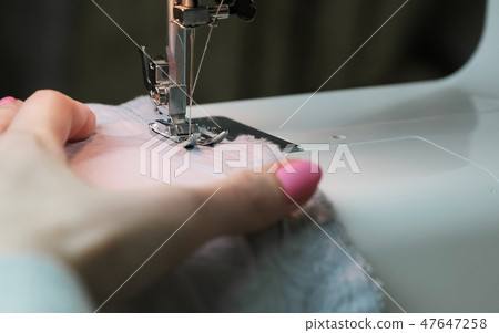 Close-up woman's hands sewing fabric on sewing machine. 47647258