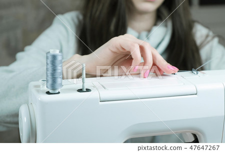 Seamstress prepare the sewing machine to work. Takes the thread 47647267