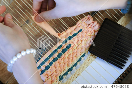 Closeup woman's hands weaving on a loom frame. 47648058
