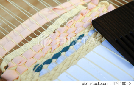 Closeup weaving on a loom frame. 47648060
