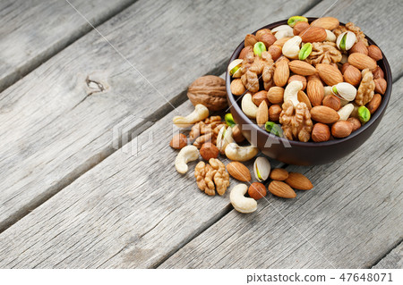 Wooden bowl with mixed nuts on a wooden gray Wooden bowl with mixed nuts on a wooden gray 47648071