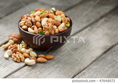 Wooden bowl with mixed nuts on a wooden gray Wooden bowl with mixed nuts on a wooden gray 47648072