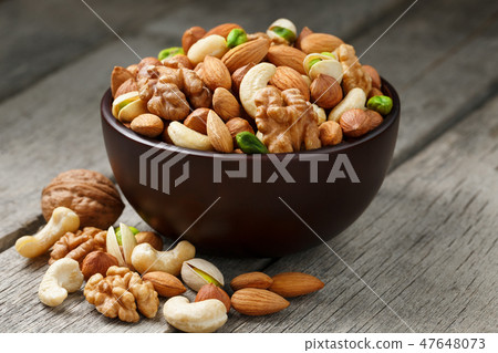 Wooden bowl with mixed nuts on a wooden gray Wooden bowl with mixed nuts on a wooden gray 47648073
