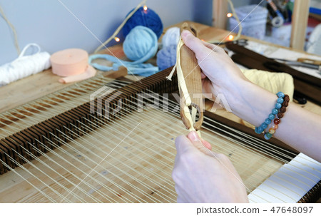 Weaving on a loom frame. Closeup woman's hands spool of yellow thread on the shuttle. Weaving on a loom frame. Closeup woman's hands spool of yellow thread on the shuttle. 47648097