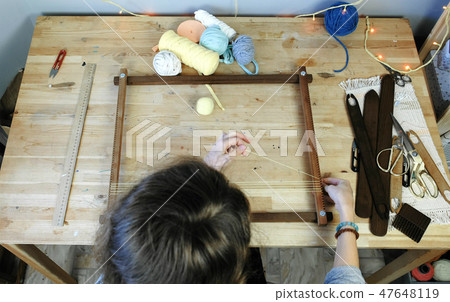 Weaving on a loom frame. Woman puts the thread in the frame for weaving. Weaving on a loom frame. Woman puts the thread in the frame for weaving. 47648119
