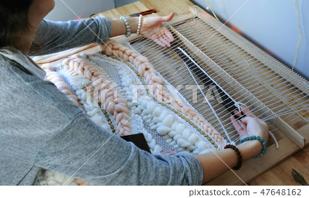 Weaving on a loom. Closeup woman's hands running on a loom. Threading the shuttle through the Weaving on a loom. Closeup woman's hands running on a loom. Threading the shuttle through the 47648162