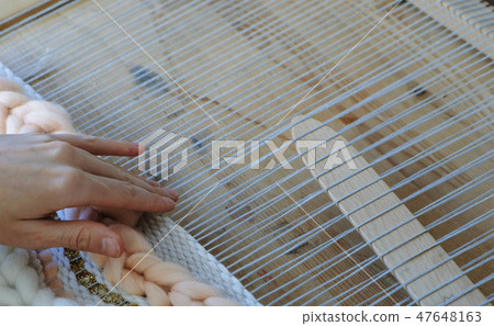 Weaving on a loom. Closeup woman's hands running on a loom. Weaving on a loom. Closeup woman's hands running on a loom. 47648163