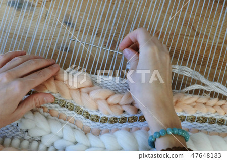 Weaving on a loom. Weaving on a loom. Closeup woman's hands running on a loom. Threading the needle 47648183