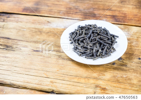Close-up fermented Ivan-tea in white plate on wooden background. Dry herbal natural tea. 47650563