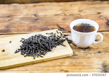 Fermented Ivan-tea on wooden board Dry herbal natural tea. White cup with Ivan-tea Top view 47650567