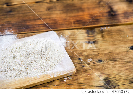 Close-up heap with rye flour coarse on a wooden board. Left on the photo. 47650572