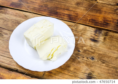 Fresh farm piece of butter on a white plate on wooden background Farm products Plate on the left at 47650714