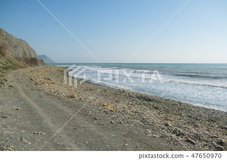 Pebble beach with mountains and cliffs. A windy day at sea. Pebble beach with mountains and cliffs. A windy day at sea. 47650970