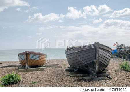 Two boiled wood boats listed on the gravel beach 47651011
