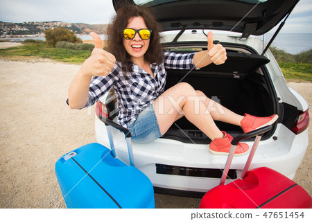 Young woman sitting in back of car smiling and showing thumbs up. Girl laughing sitting in the open 47651454
