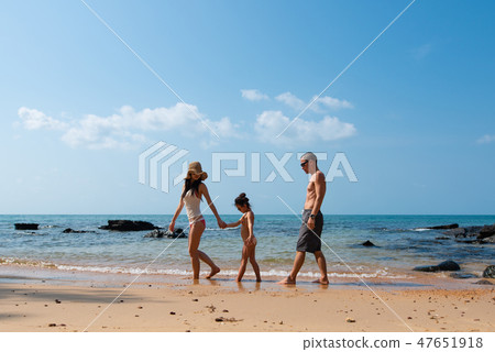 Father and mother and daughter playing on the beach Father and mother and daughter playing on the beach 47651918